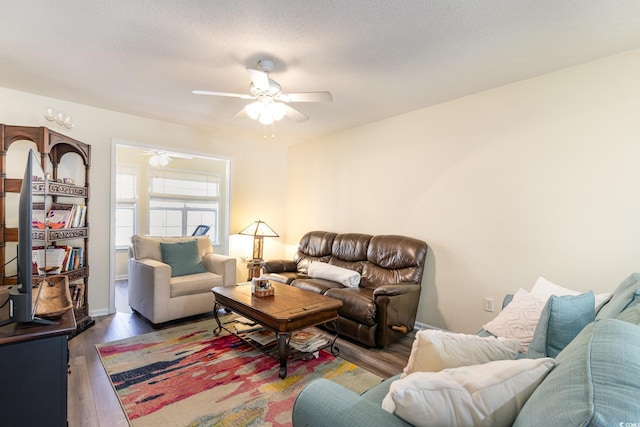 living room with a textured ceiling, wood finished floors, and a ceiling fan