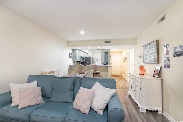 living area featuring baseboards, visible vents, and wood finished floors