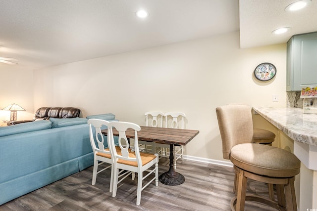 dining area featuring baseboards, wood finished floors, and recessed lighting