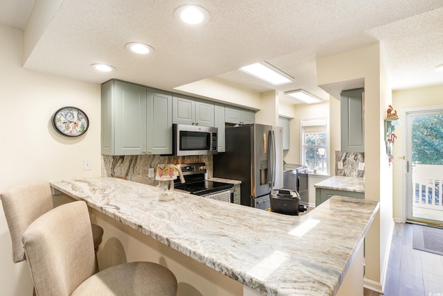 kitchen with a peninsula, a kitchen breakfast bar, appliances with stainless steel finishes, backsplash, and washing machine and clothes dryer