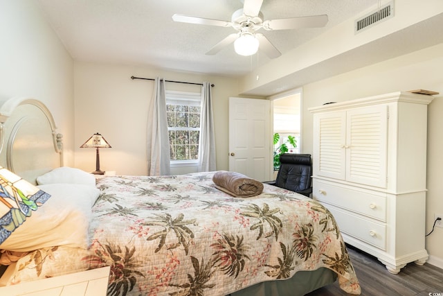 bedroom featuring dark wood-style floors, ceiling fan, visible vents, and a textured ceiling