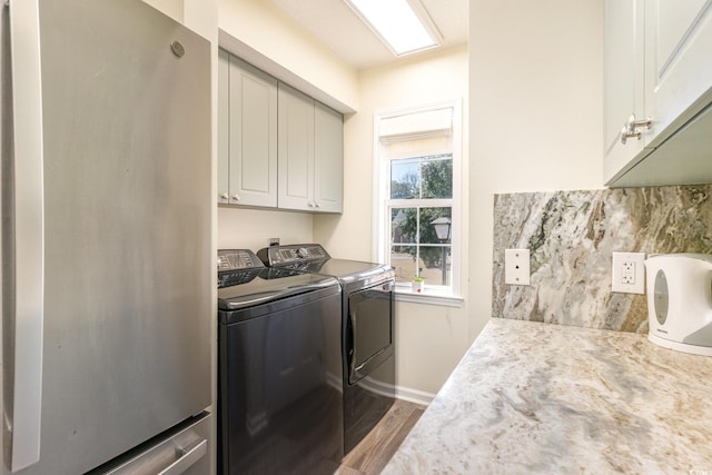 laundry area featuring washer and dryer, cabinet space, and wood finished floors