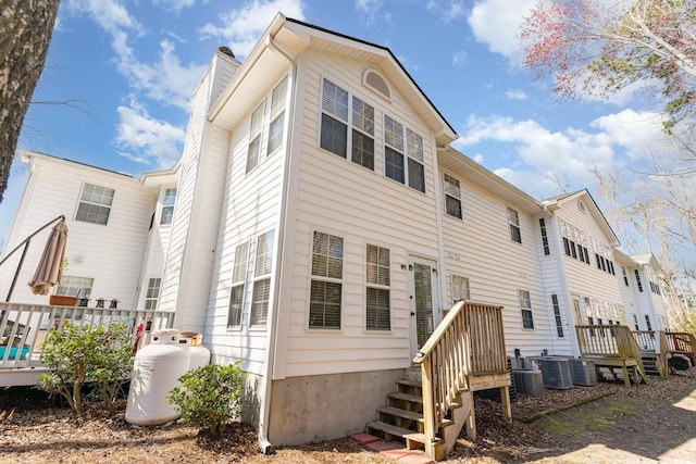 back of property featuring a chimney, central AC unit, and a wooden deck