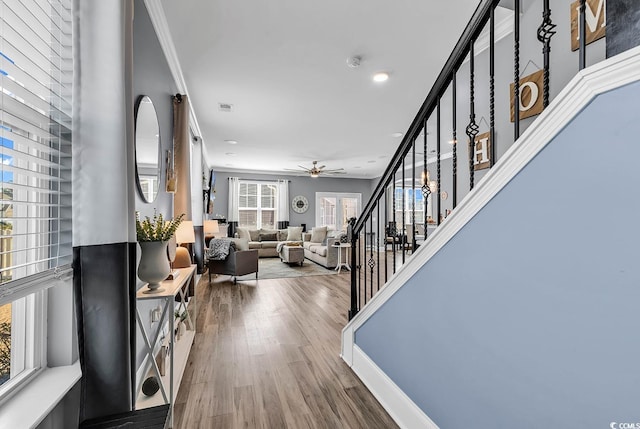 entrance foyer with crown molding, visible vents, a ceiling fan, wood finished floors, and stairs