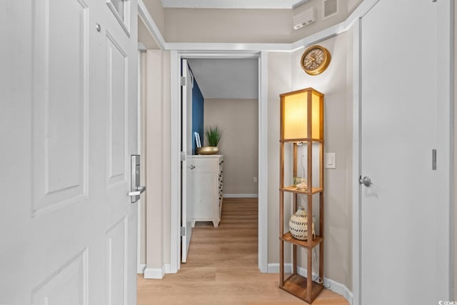 hallway with light wood-type flooring, visible vents, and baseboards