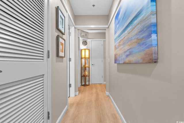 corridor with light wood-style floors and baseboards