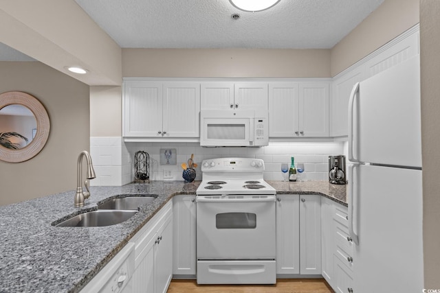 kitchen featuring white appliances, tasteful backsplash, white cabinetry, and a sink