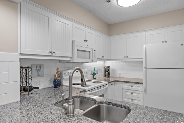 kitchen with white appliances, tasteful backsplash, white cabinets, a textured ceiling, and a sink