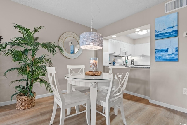 dining area featuring light wood finished floors, baseboards, and visible vents