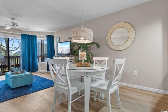 dining area with a ceiling fan, a textured ceiling, baseboards, and wood finished floors