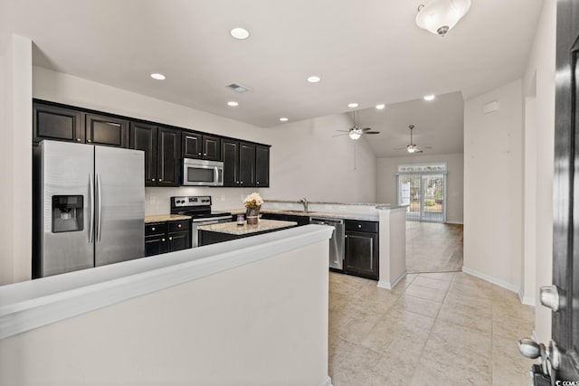 kitchen with stainless steel appliances, visible vents, a sink, dark cabinets, and a peninsula