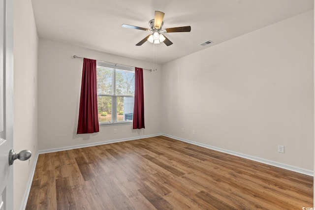 unfurnished room featuring visible vents, ceiling fan, baseboards, and wood finished floors