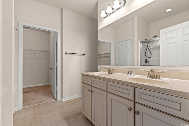 bathroom with a stall shower, a sink, baseboards, and double vanity