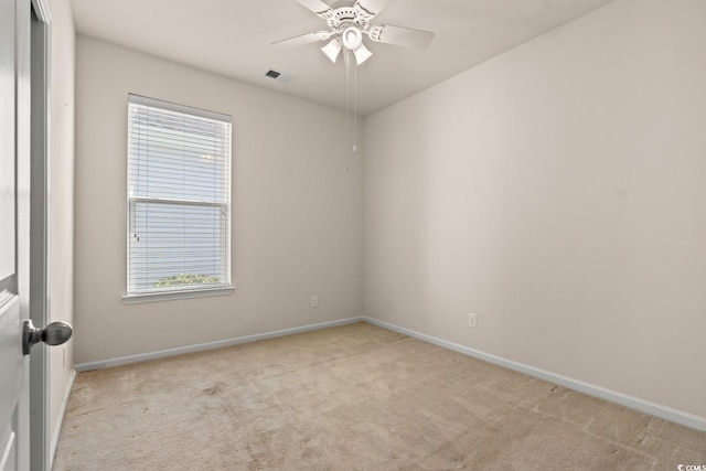 spare room with a wealth of natural light, light carpet, ceiling fan, and baseboards