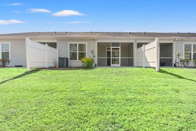 rear view of house with a sunroom, central AC unit, and a yard