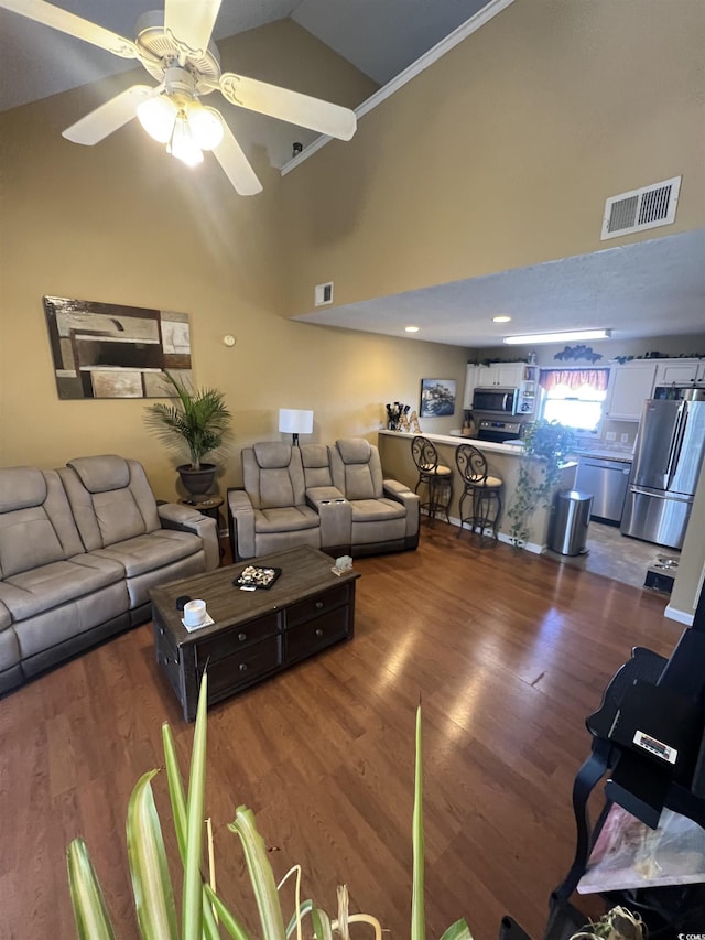 living room featuring dark wood-type flooring, visible vents, and a ceiling fan