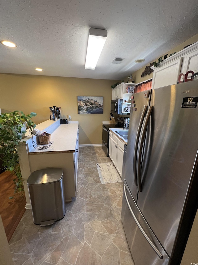 kitchen featuring appliances with stainless steel finishes, white cabinets, visible vents, and a textured ceiling