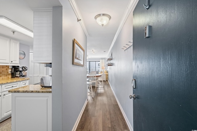 corridor with ornamental molding, baseboards, and wood finished floors