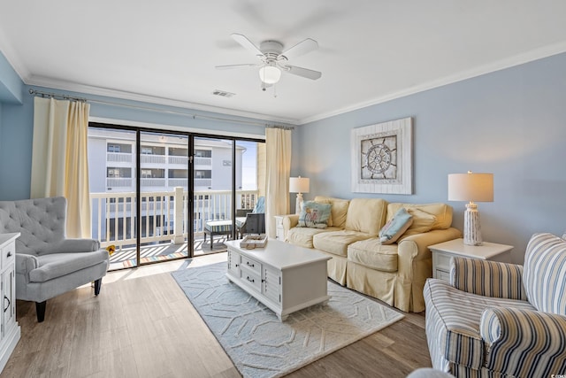 living area featuring ceiling fan, visible vents, crown molding, and wood finished floors