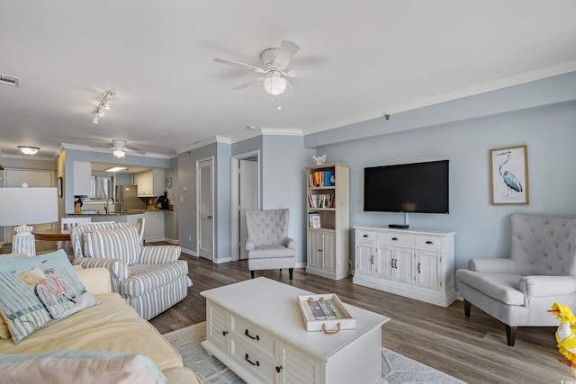 living area with visible vents, ornamental molding, a ceiling fan, wood finished floors, and baseboards