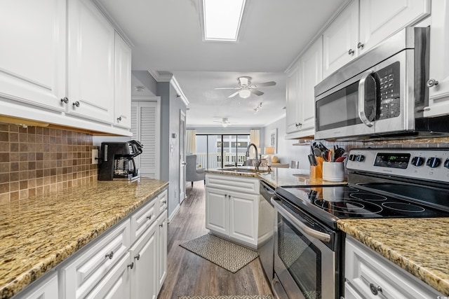 kitchen featuring stainless steel appliances, white cabinets, a sink, and a peninsula