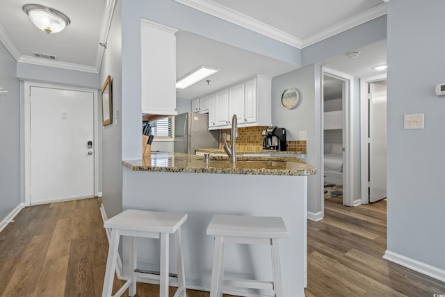 kitchen with crown molding, visible vents, decorative backsplash, freestanding refrigerator, and a sink