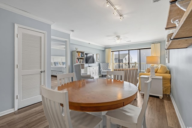 dining room with baseboards, a ceiling fan, ornamental molding, wood finished floors, and rail lighting