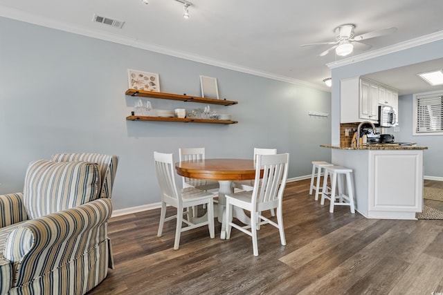 dining room with dark wood-type flooring, visible vents, crown molding, and baseboards