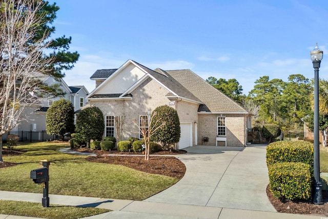 traditional home featuring a garage, brick siding, fence, concrete driveway, and a front lawn