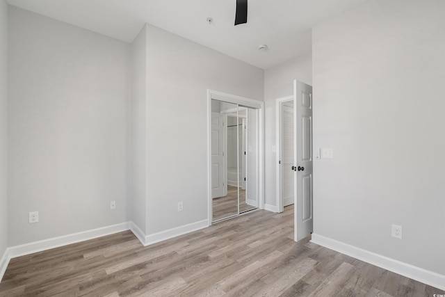 unfurnished bedroom with ceiling fan, a closet, wood finished floors, and baseboards