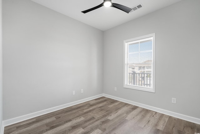 spare room with ceiling fan, wood finished floors, visible vents, and baseboards