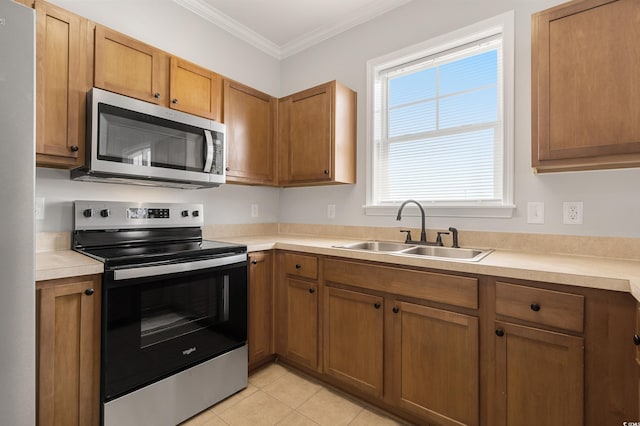 kitchen featuring appliances with stainless steel finishes, light countertops, a sink, and ornamental molding