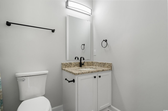 bathroom featuring baseboards, vanity, and toilet