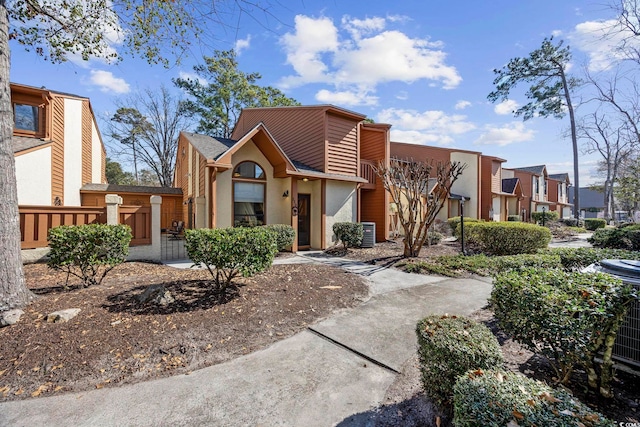 view of front of home featuring fence, central AC unit, and a residential view