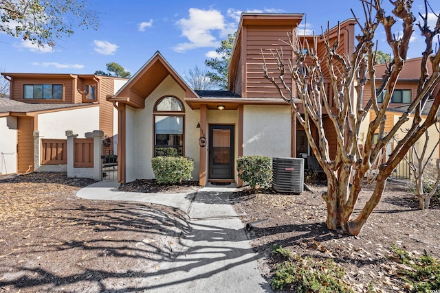 view of front of home featuring cooling unit, fence, and stucco siding