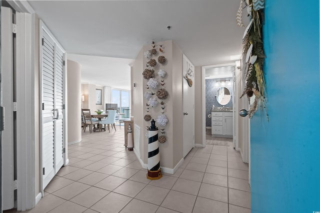 hall featuring light tile patterned floors and baseboards