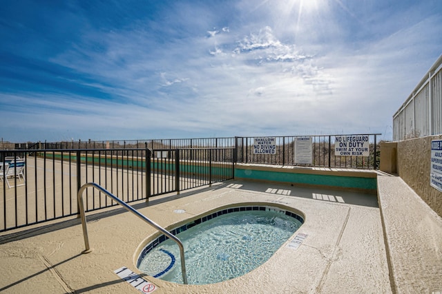 view of swimming pool with a hot tub and fence