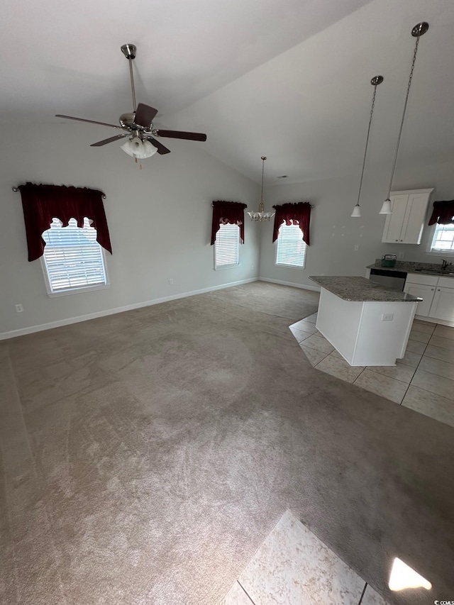 kitchen with light colored carpet, dark countertops, lofted ceiling, a kitchen island, and white cabinetry