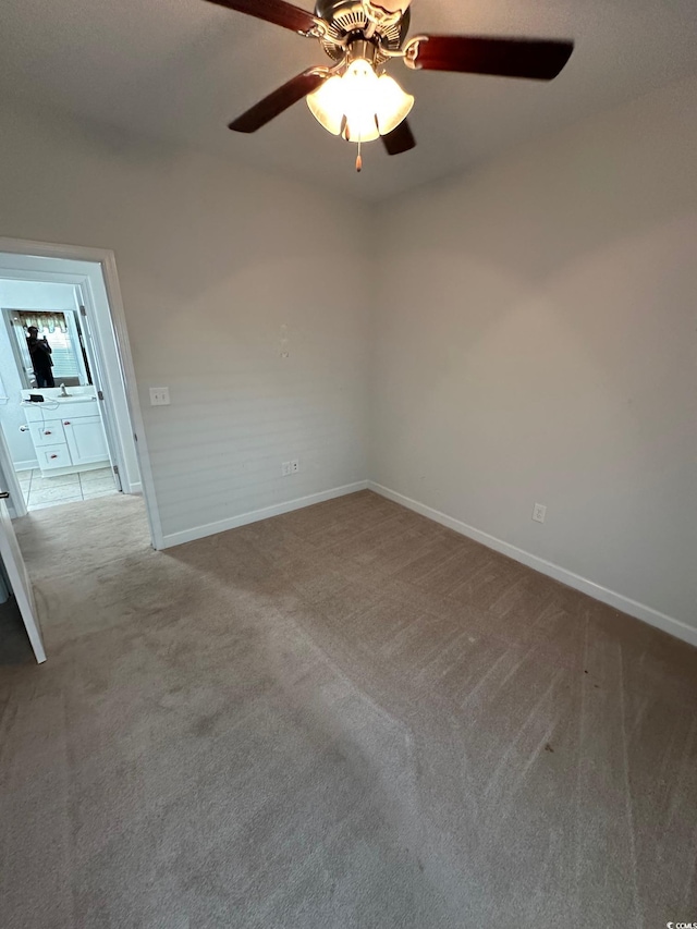 unfurnished room with carpet flooring, a ceiling fan, and baseboards