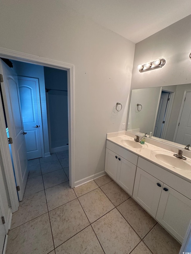 full bath with double vanity, tile patterned flooring, a sink, and baseboards