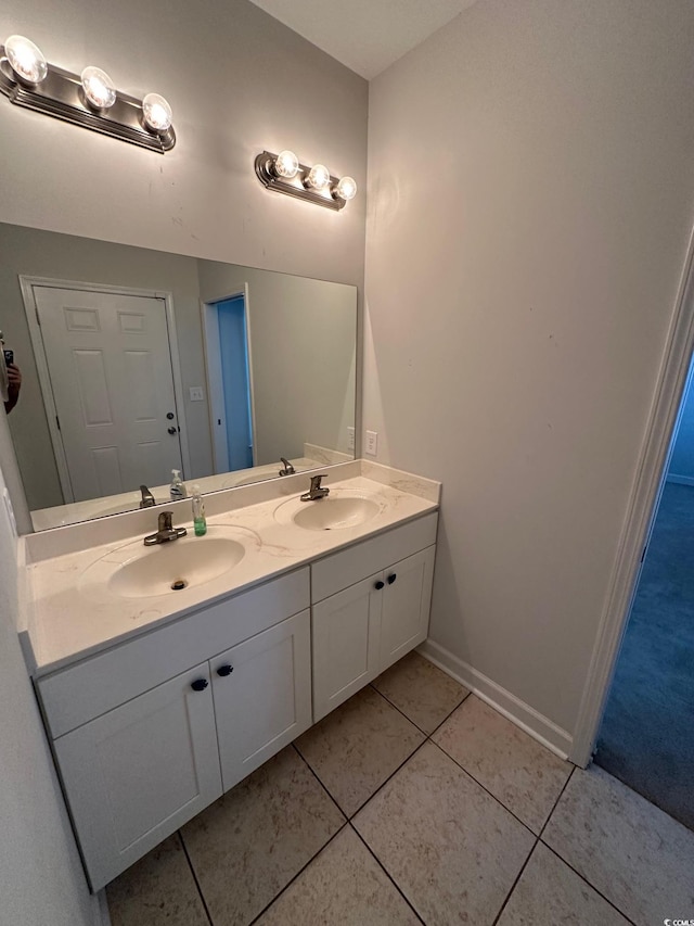 full bath with double vanity, tile patterned flooring, baseboards, and a sink