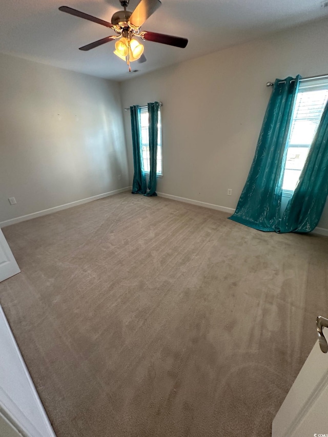 empty room with light colored carpet, ceiling fan, and baseboards