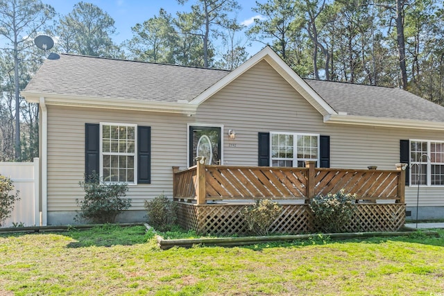 ranch-style home with a shingled roof, fence, a deck, and a front yard