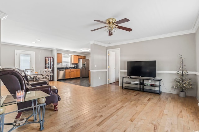 living area with a ceiling fan, ornamental molding, and hardwood / wood-style floors