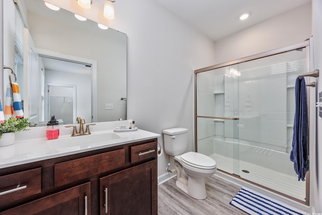 bathroom with toilet, a shower stall, vanity, and wood finished floors