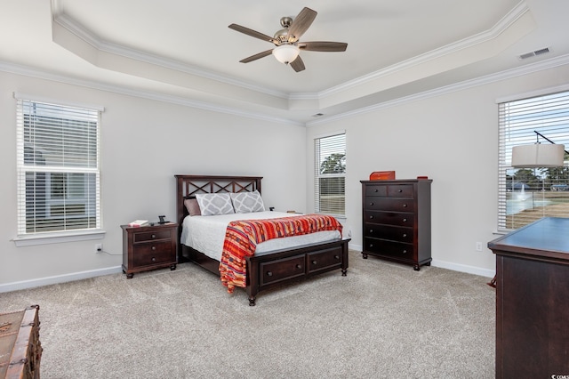 carpeted bedroom featuring baseboards, visible vents, a ceiling fan, a tray ceiling, and crown molding