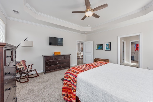 carpeted bedroom with visible vents, a tray ceiling, baseboards, and ornamental molding