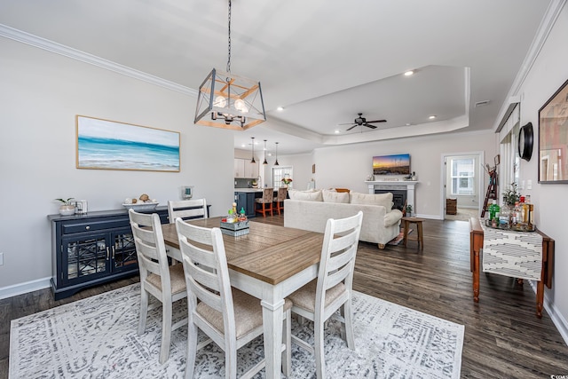 dining room with baseboards, ornamental molding, a tray ceiling, and ceiling fan with notable chandelier