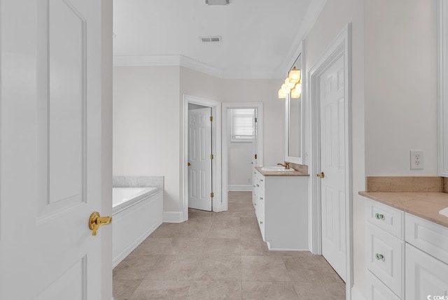 bathroom with baseboards, ornamental molding, two vanities, a garden tub, and a sink