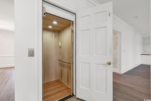 interior space with recessed lighting, wood finished floors, baseboards, elevator, and crown molding